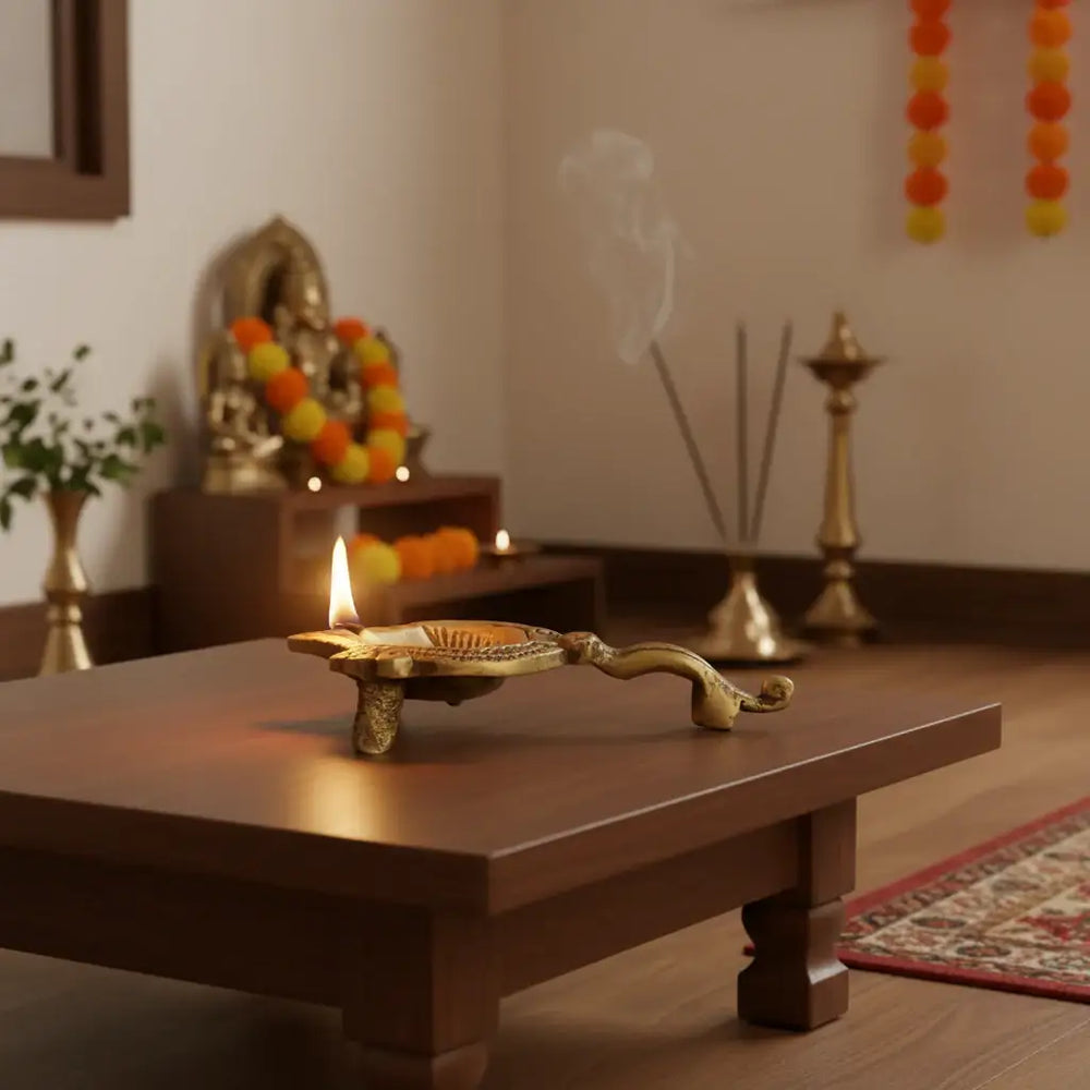 Close-up of a golden brass aarti diya with a handle, featuring an Om symbol embossed in the center of the oil lamp bowl.