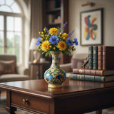 A blue pottery vase with a bulbous base and slender neck, featuring a hand-painted yellow background with intricate blue, green, and red floral designs, isolated on a white background.