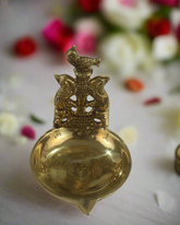 Decorative brass oil lamp with intricate design on a textured fabric background