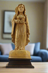 Statue of a religious figure on a pedestal with flowers in the background