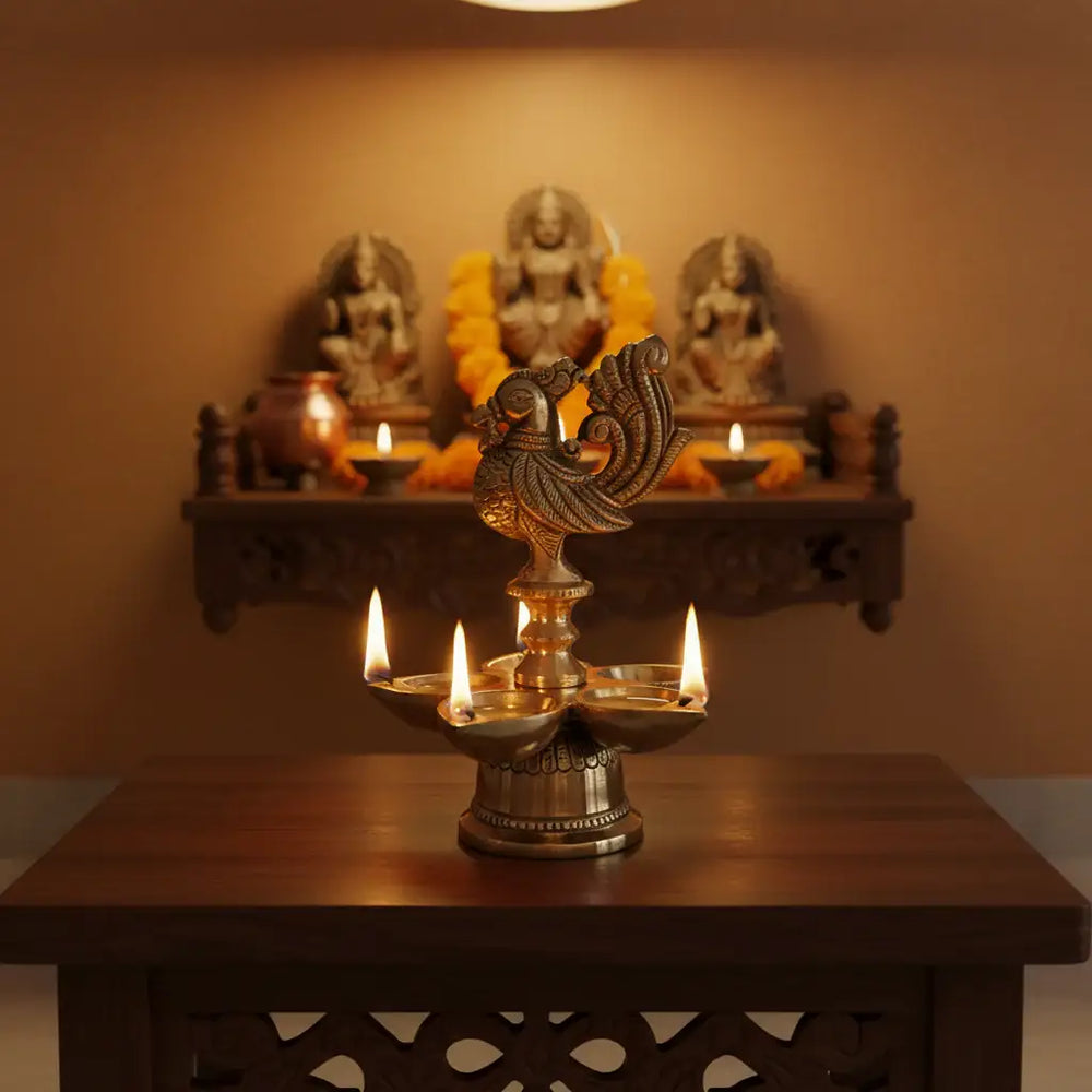 A golden brass five-wick oil lamp (Pancha Mukhi Diya) featuring a detailed peacock figure on top, with five small deepak bowls arranged around its base, against a light textured background.