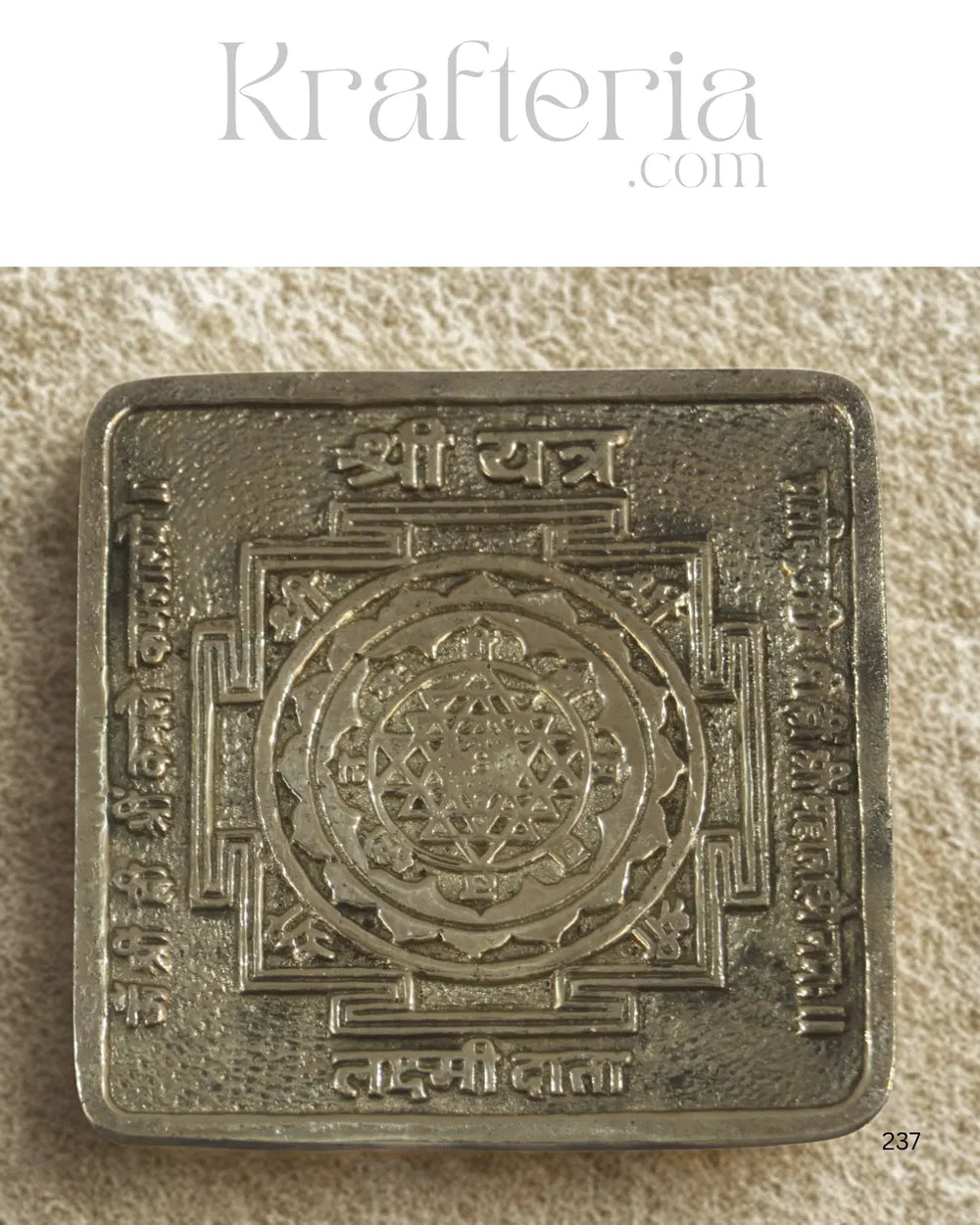 Decorative metal square with intricate designs on a textured beige background