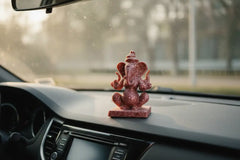 Handcrafted red marble two-sided Ganesha idol with detailed carving.