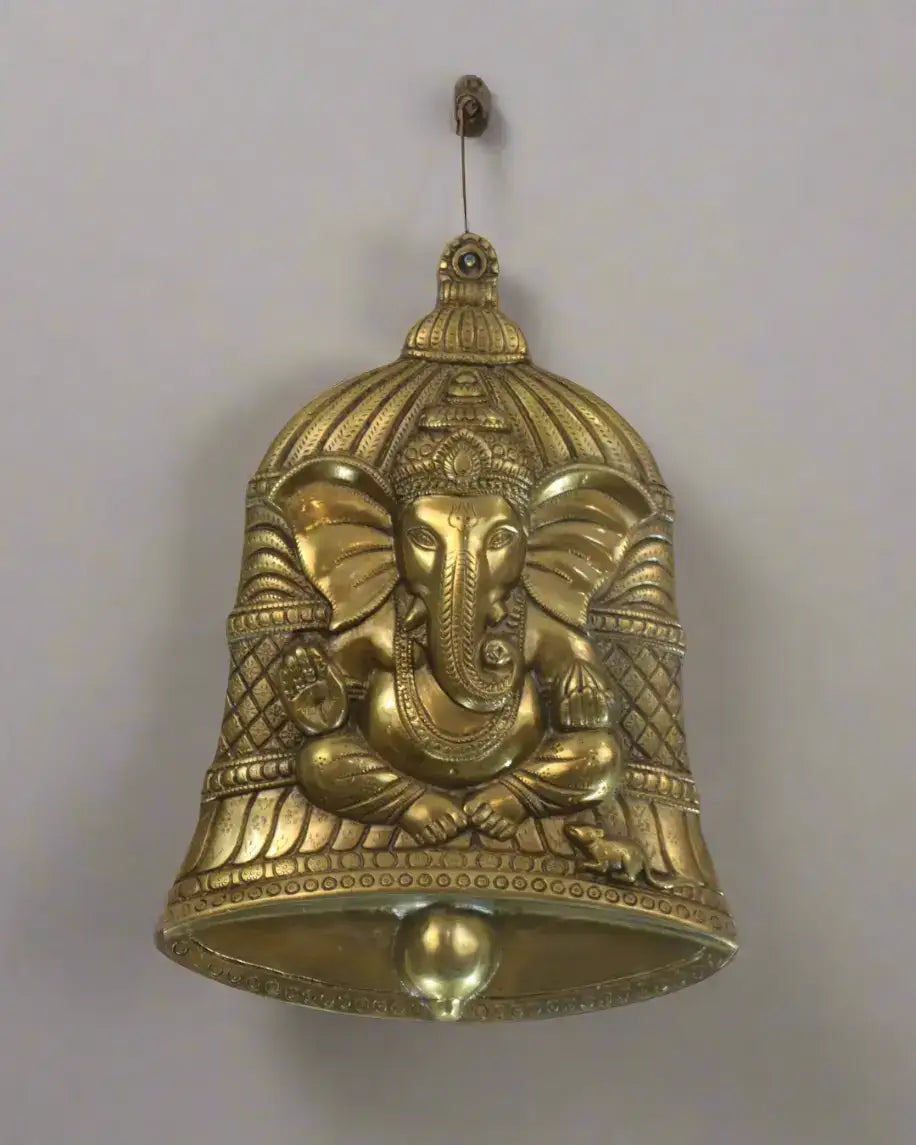 Decorative brass bell with elephant design on a textured brown background