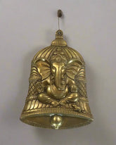 Decorative brass bell with elephant design on a textured brown background