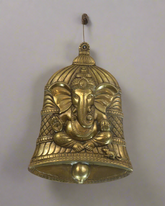 Decorative brass bell with elephant design on a textured brown background