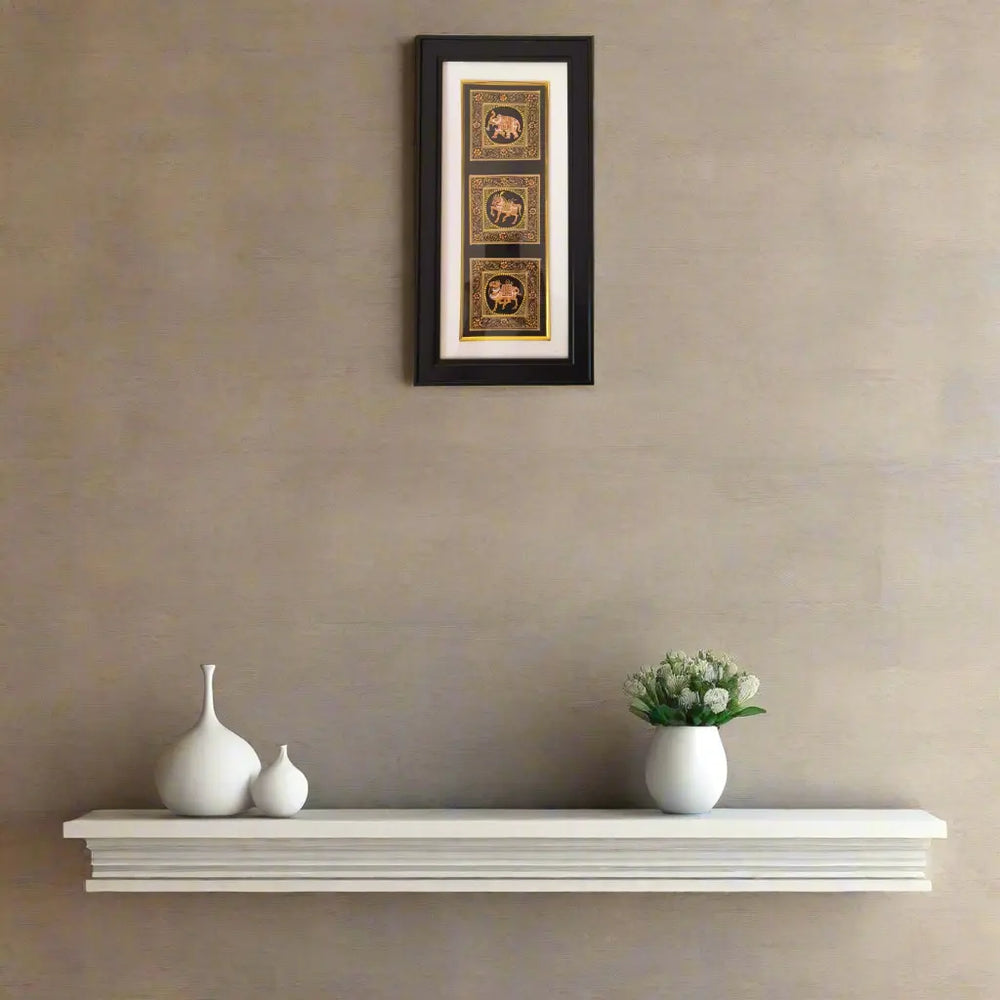 Miniature Painting Framed artwork above a white shelf with decorative vases and a small plant on a beige wall.