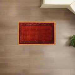 Red doormat with a geometric pattern on a wooden floor