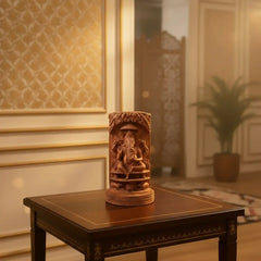Intricately hand-carved cylindrical wooden sculpture depicting Lord Ganesha and sacred cow scenes with fine detailing