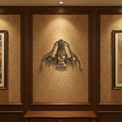 A detailed brass wall hanging depicting the face of Lord Venkateswara, adorned with a tall crown, traditional markings, and flanked by symbolic conch and discus motifs.