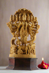 Gold-colored statue with multiple faces on a pedestal indoors
