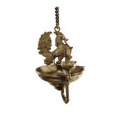 Brass peacock hanging diya, a traditional oil lamp, ornate metalwork.