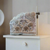Decorative stone block with intricate carvings on a white background