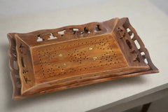 Wooden cribbage board with intricate carvings on a white surface