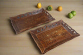Two wooden trays with intricate carvings on a white surface