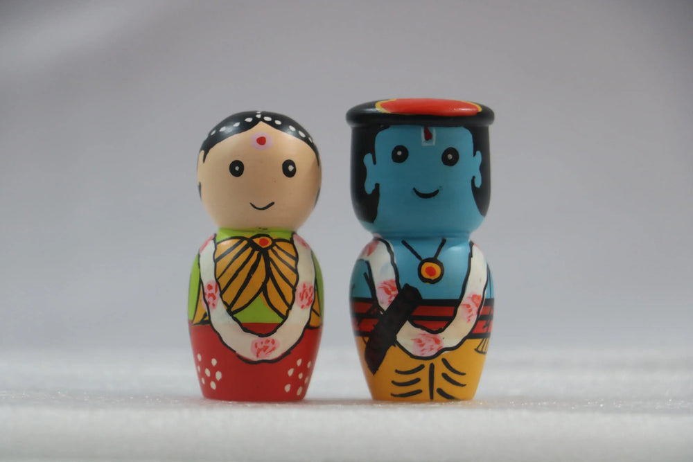 Radha krishna Two colorful wooden dolls with traditional designs on a gray background