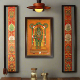 Decorative wall art with a central figure framed by ornate borders on a gray wall.