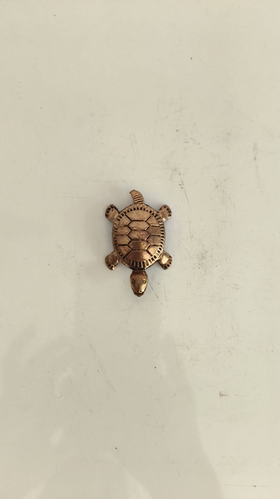 Small bronze turtle figurine with detailed shell pattern on a white background.
