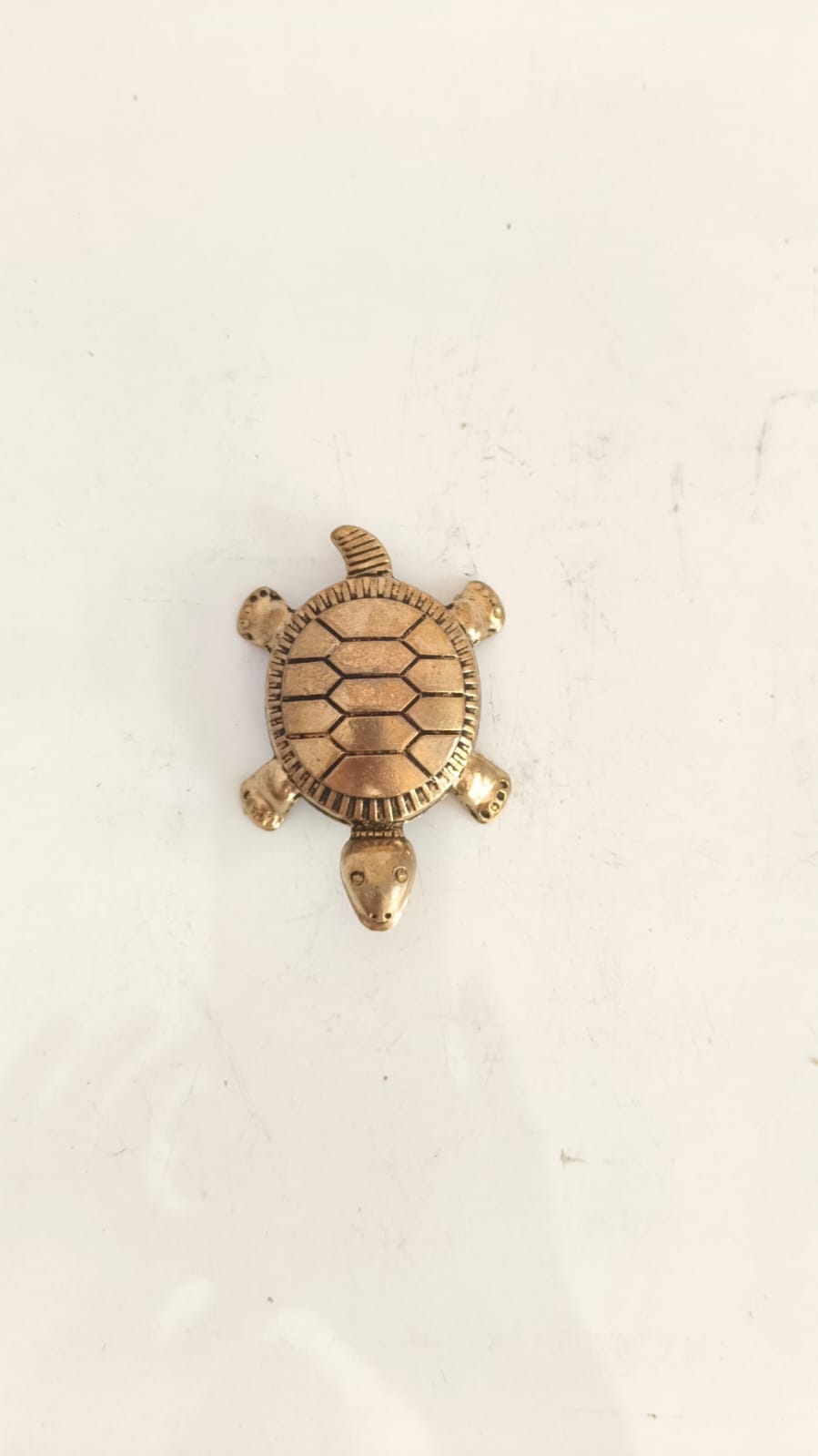 Small bronze turtle figurine with detailed shell pattern on a white background.