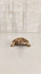 Small bronze turtle figurine with detailed shell pattern on a white background.