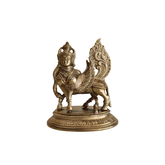 Front view of a shiny brass Kamadhenu Kalpavriksha cow statue with a human head, wings, and an ornate tail on a decorative