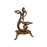 Antique brass peacock oil lamp stand with ornate base and three legs, used for pooja and home decor.
