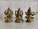 Brass statues of Lakshmi, Ganesha, and Saraswati seated in a row, part of the Lakshmi Ganesha Saraswati statue set.