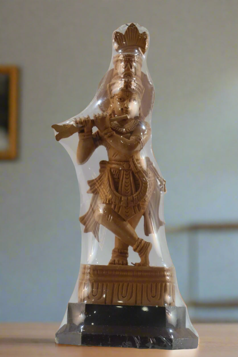 Statue of a deity with a crown and musical instrument in a clear display case, brand 'Krafleria' visible.