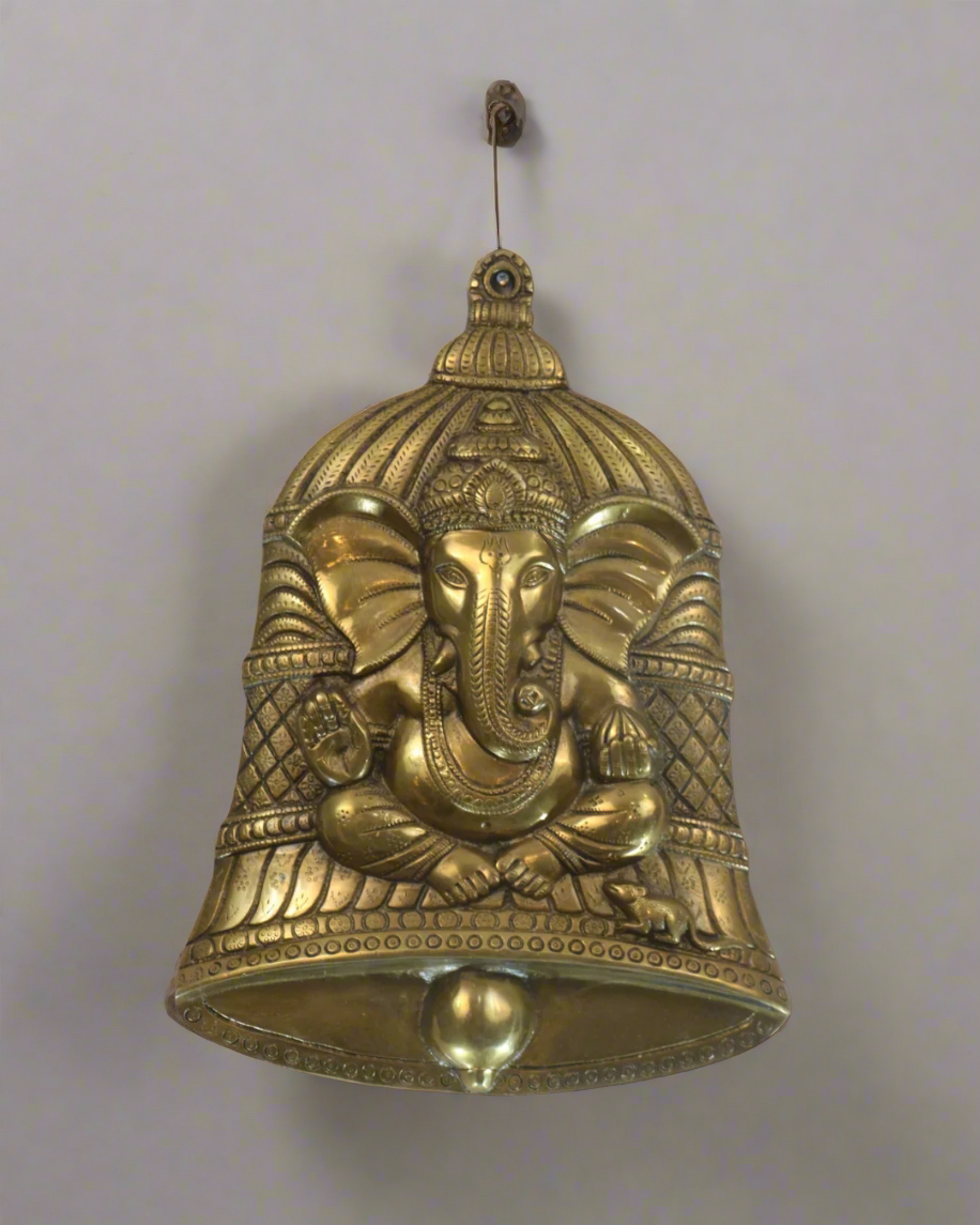 Decorative brass bell with elephant design on a textured brown background