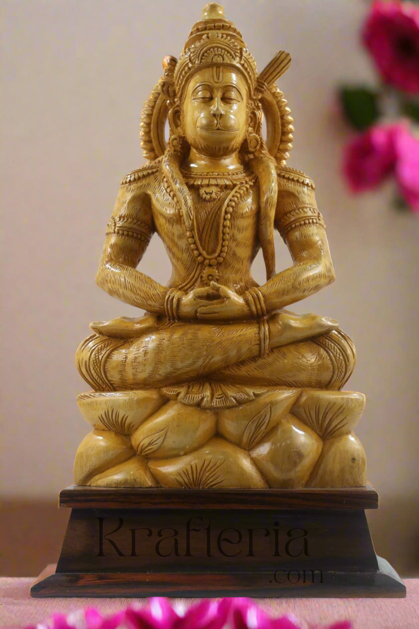 Gold-colored statue of a seated figure on a wooden base with a textured wall background