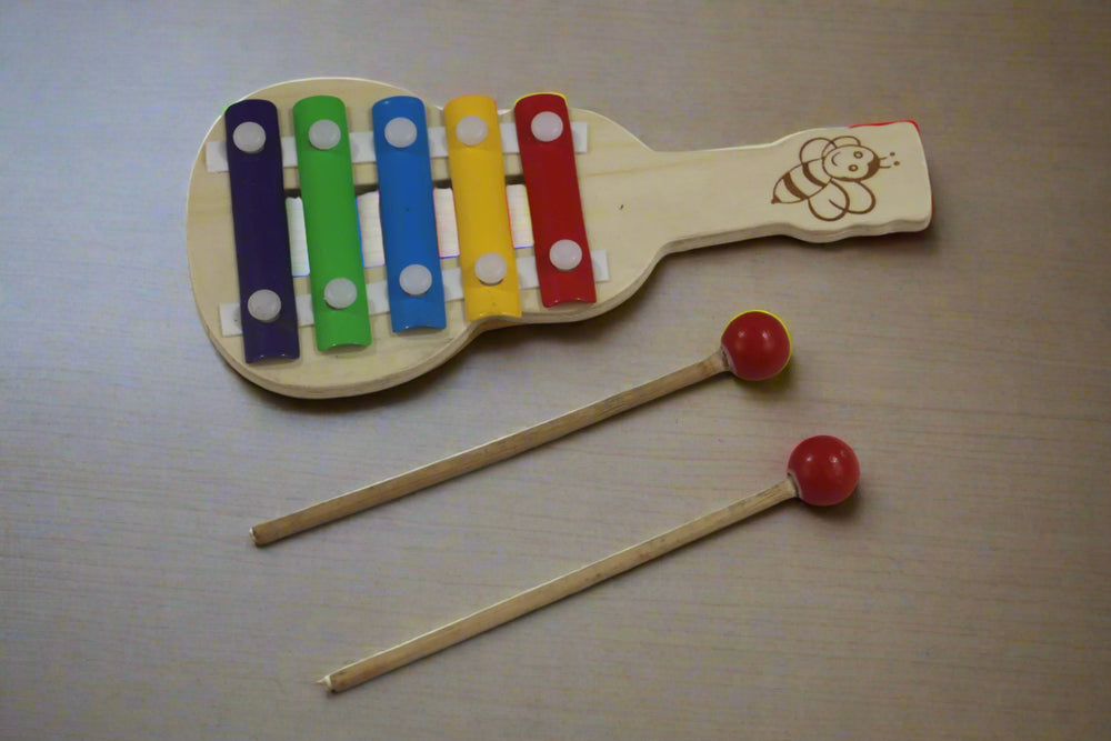 Wooden toy xylophone with colorful keys and two mallets on a white background
