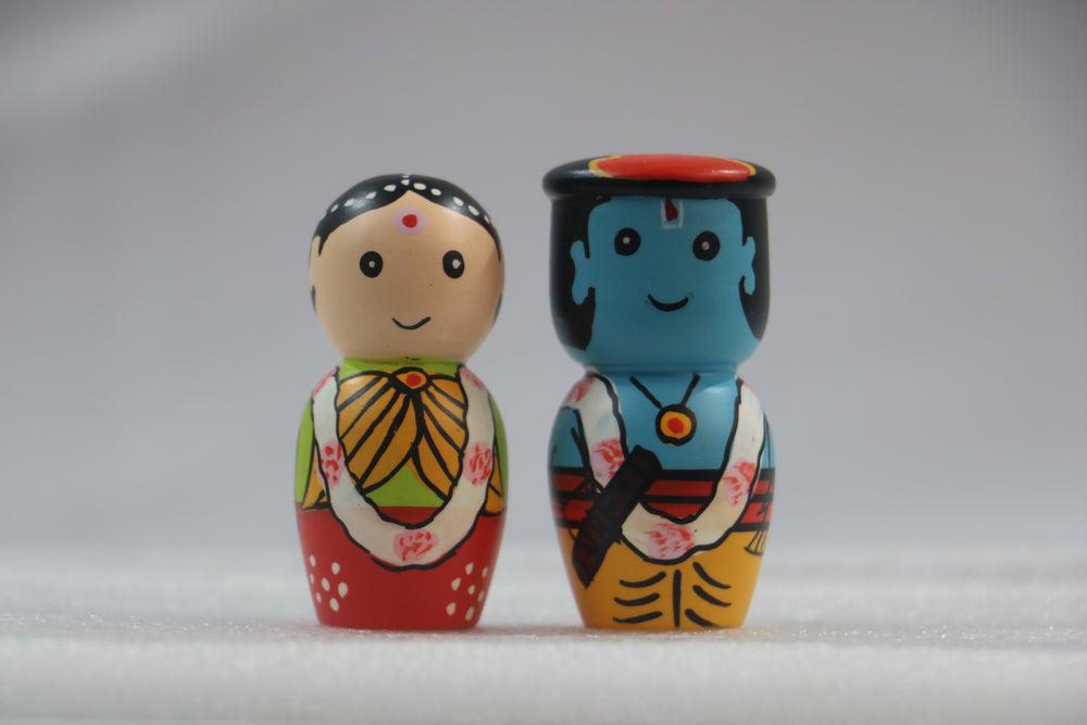 Radha krishna Two colorful wooden dolls with traditional designs on a gray background