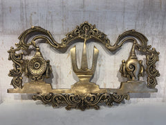 An ornate brass wall hanging displaying the U-shaped Venkateswara Namam (tilak) in the center, flanked by the Shankha (conch) and Chakra (discus) symbols, with decorative border work.