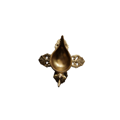 Side view of a handcrafted brass peacock diya oil lamp with an ornate four-pointed base, on a white background.