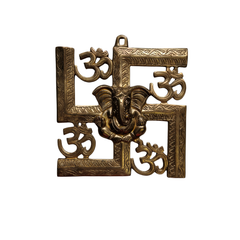 A brass swastik wall hanging with a central Ganesha figure and Om symbols.